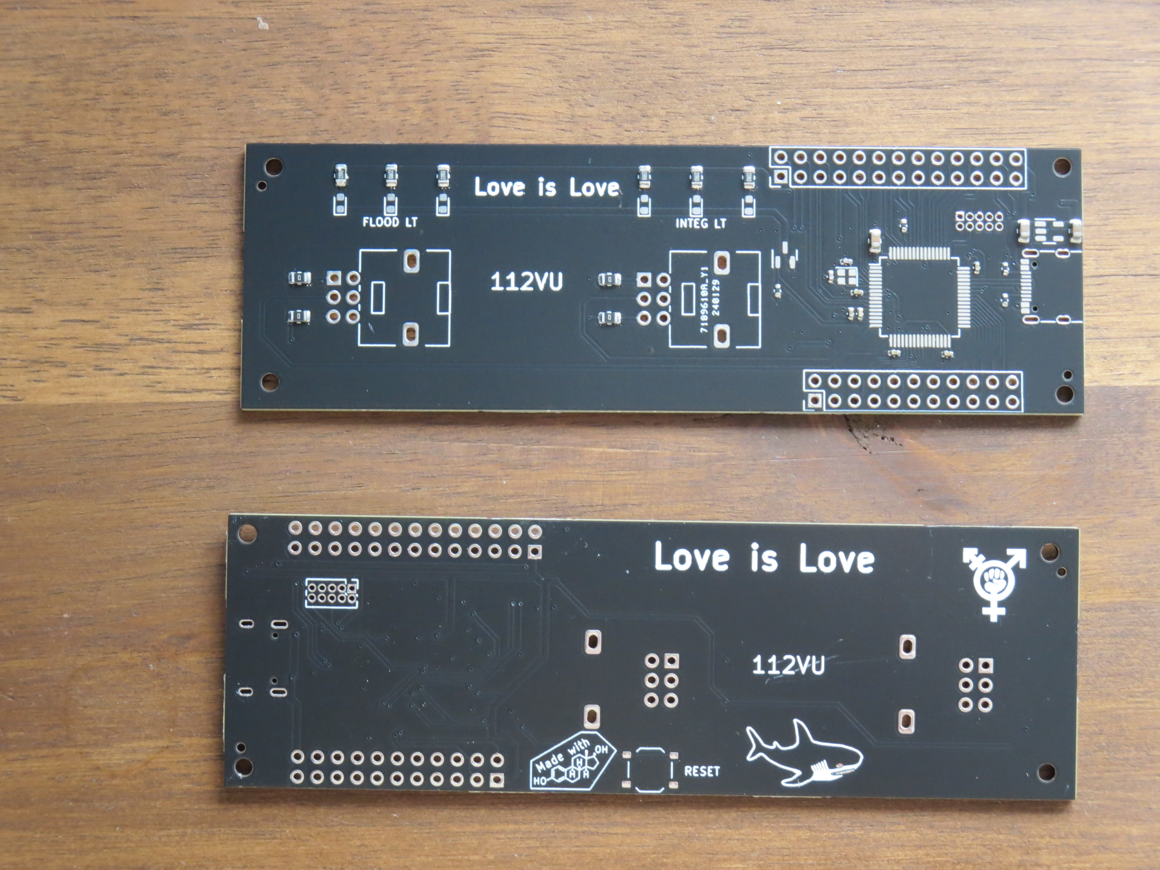 Two PCBs showing front and backside of the same design. The front has some SMD components, some already soldered some not, pads for a microcontroller and a USB C port, mounts for potentiometers and pinheaders as well at silk screen labels '112VU' (the panels identifier) and 'Love is Love'. The backside show mostly just traces and the through holes from components from the front. It also has silk screen art, showing a Made with Estrogen icon, a blahaj and a transgender sign as well as again the writing 'Love is Love'